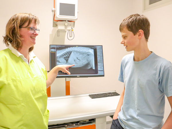 Frau Kolbig zeigt auf den Röntgenbildschirm einem Teenager den Bauch eines Tieres